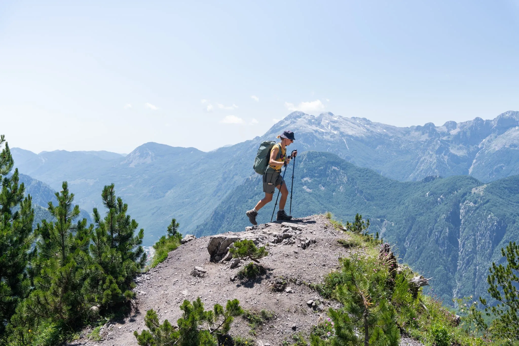 Hiker with trekking poles on a rocky ridge above the Accursed Mountains